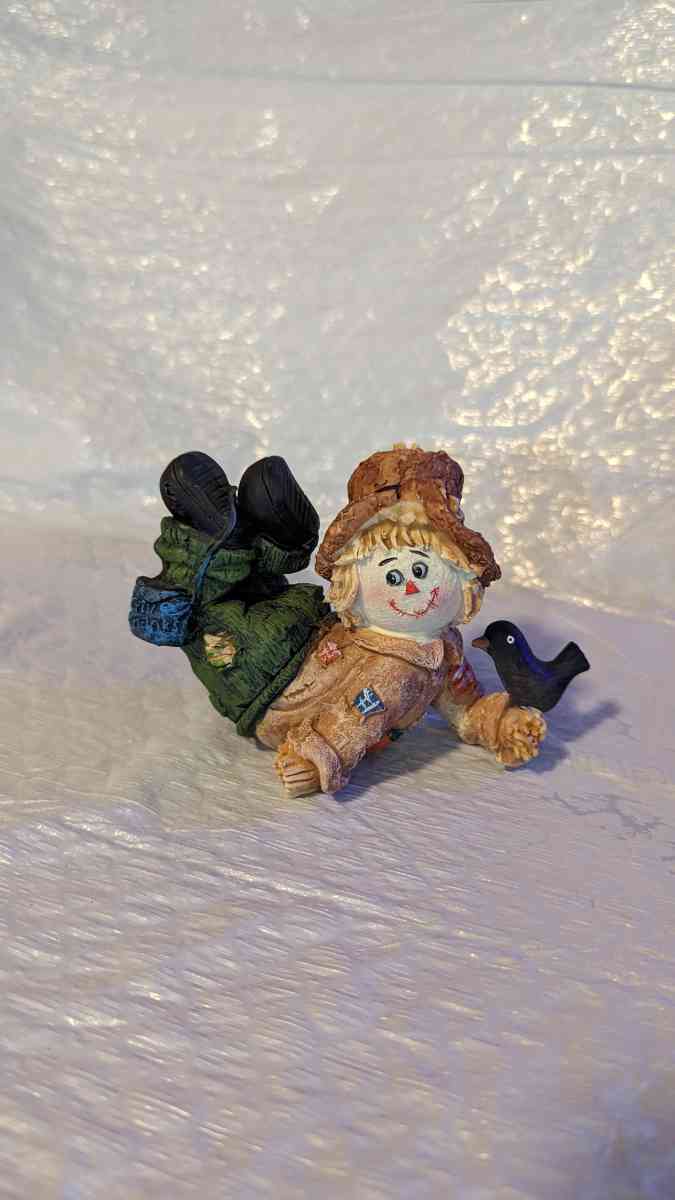 Resin Scarecrow Laying Down With Legs Bent Holding A Crow - Phoenix, Arizona