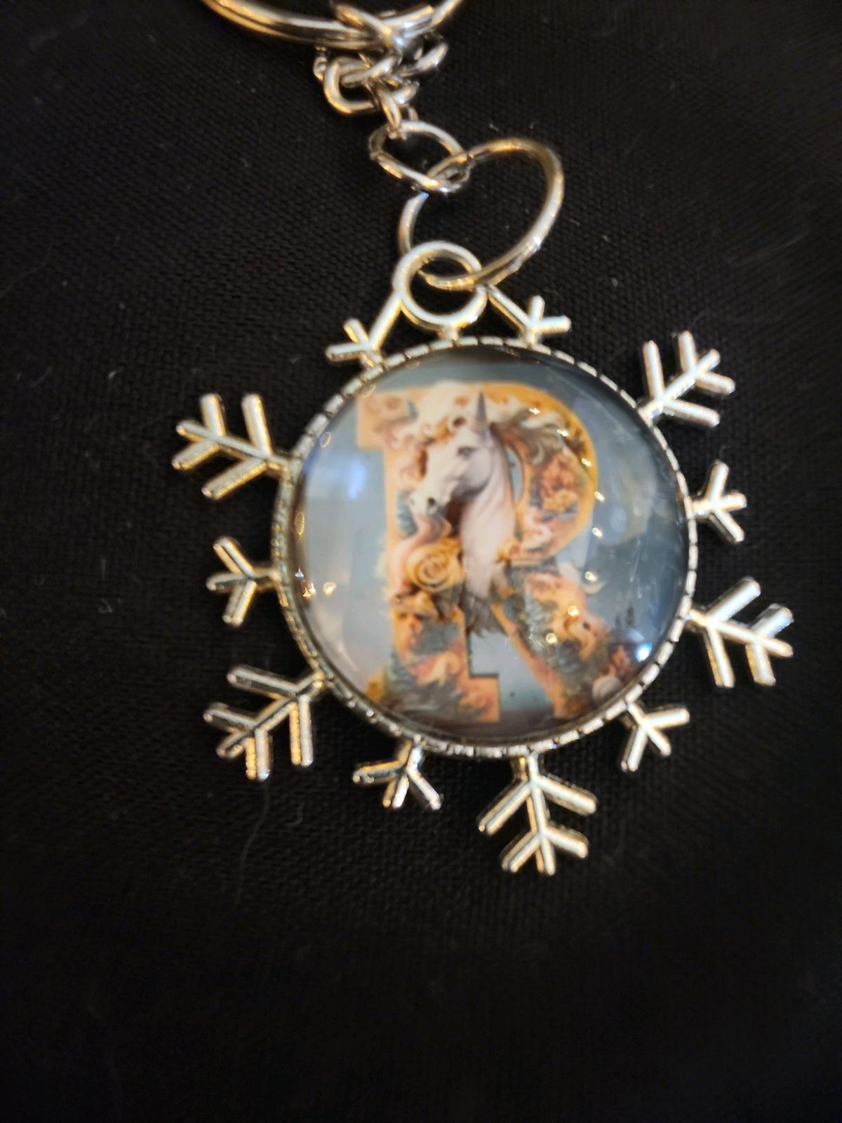 a snowflake pendant with a unicorn and the letter R